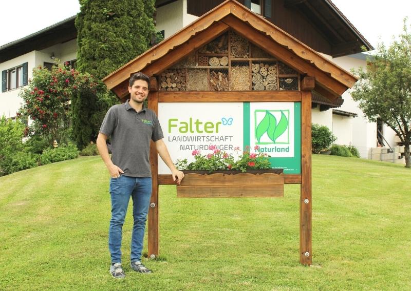 Johann Falter vor der Stele mit Nisthilfe, auf dem Schild steht Naturland und Falter Landwirtschaft, Biogas und Naturdünger